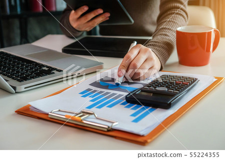 Business women calculates financials in office. Business women calculates financials in office. 55224355