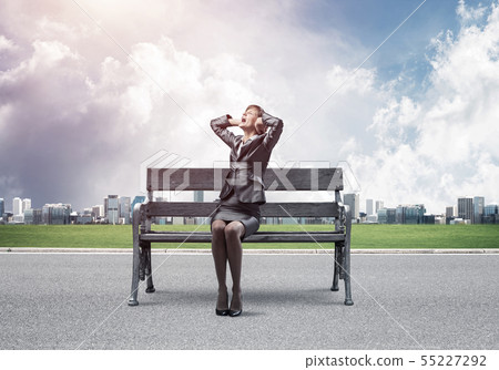 Stressful woman sitting on wooden bench Stressful woman sitting on wooden bench 55227292