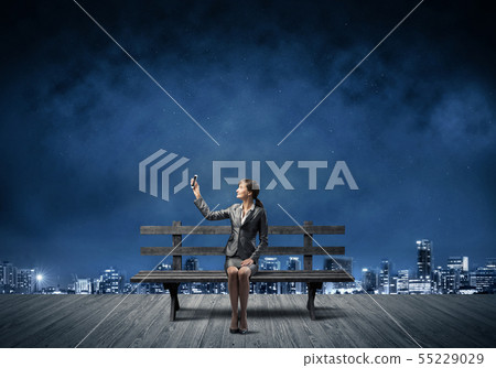 Young woman in business suit holding smartphone 55229029