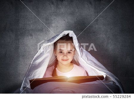 Happy little girl reading book in bed Happy little girl reading book in bed 55229284
