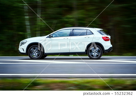 white luxury suv car goes fast through the forest 55232362