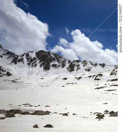 Snowy sunlit plateau with stones and blue cloudy 55234607