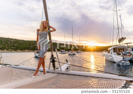 beautiful sexy woman in dress relaxing on a yacht front at sunset 55235520