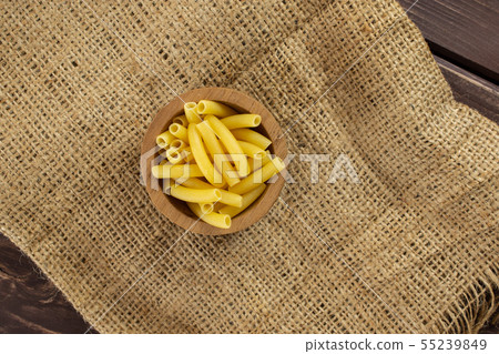Raw macaroni pasta on brown wood 55239849