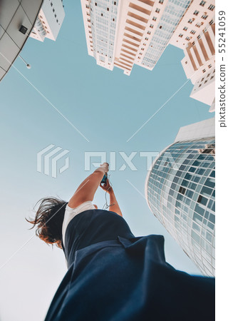 A girl is taking pictures of a new residential complex White modern skyscrapers. A girl is taking pictures of a new residential complex White modern skyscrapers. 55241059