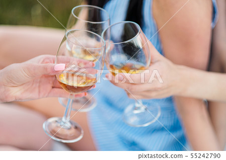 Three female hands with glasses of white wine. Toast, congratulations on an outdoor picnic. The 55242790