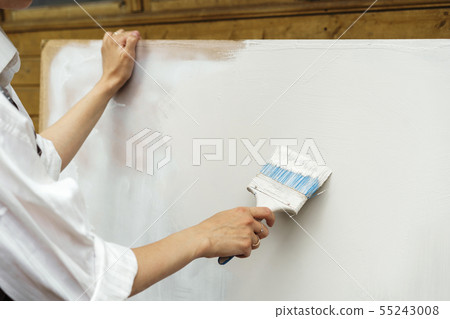 Female hand with brush paints a white sheet. Clear sheet Female hand with brush paints a white sheet. Clear sheet 55243008