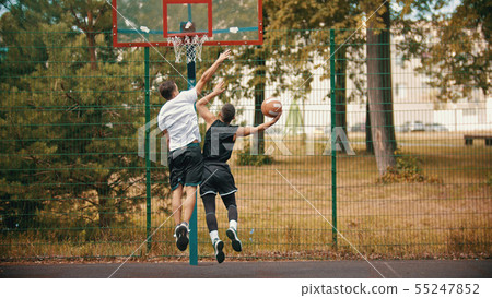Young men playing basketball on the sports ground outdoors - protecting the basketball hoop from Young men playing basketball on the sports ground outdoors - protecting the basketball hoop from 55247852