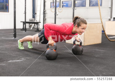 Young woman trains pushups with kettlebells 55257288