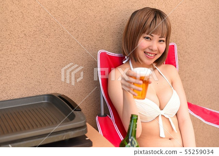 Woman 1 in swimsuit drinking beer on veranda Woman 1 in swimsuit drinking beer on veranda 55259034