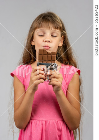 Eight-year-old girl with pleasure eats chocolate Eight-year-old girl with pleasure eats chocolate 55265422