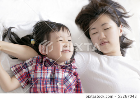 閃光說謊在床上的惡作劇面孔的小女孩和母親。幸福,家庭,愛,父母和孩子,育兒形象 閃光說謊在床上的惡作劇面孔的小女孩和母親。幸福,家庭,愛,父母和孩子,育兒形象 55267048