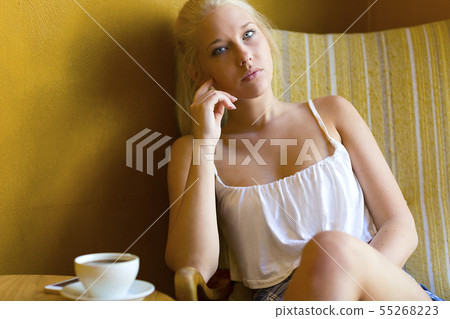 Pensive young woman at cafe with coffee and smartphone Pensive young woman at cafe with coffee and smartphone 55268223