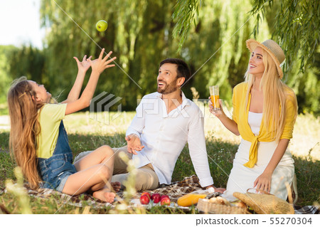 Family having picnic in nature, girl juggling with apple Family having picnic in nature, girl juggling with apple 55270304
