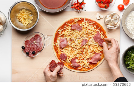 Chef decorating Italian pizza with ham and salami slices 55270693