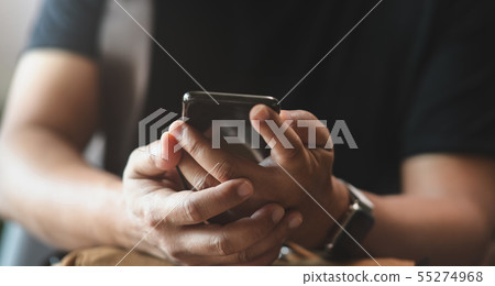 Close-up view of young man holding smartphone Close-up view of young man holding smartphone 55274968