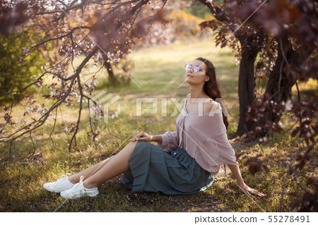 Woman Outdoors in Park Near Spring Blossom Tree Woman Outdoors in Park Near Spring Blossom Tree 55278491