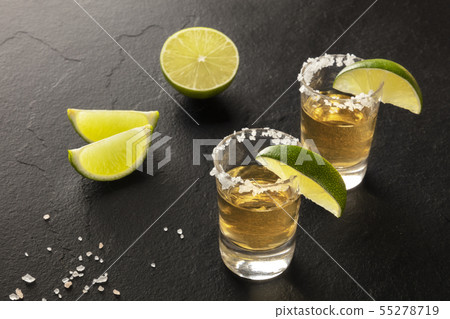 Golden tequila with lime slices on black 55278719