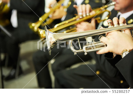 The trumpeter is playing on a silver trumpet. Trumpet players 55280257
