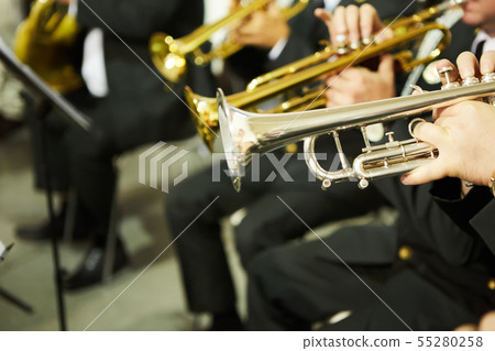 The trumpeter is playing on a silver trumpet. Trumpet players 55280258