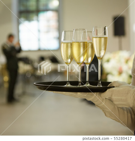 A tray with three glasses of champagne. Waiter holding a tray with a champagne glass 55280417