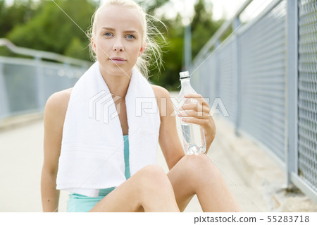 Smiling runner sitting on the ground and takes a break Smiling runner sitting on the ground and takes a break 55283718