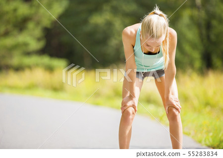 Woman leaning on knees and catch breath after stamina workout 55283834