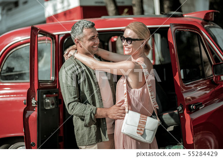 Loving couple hugging near the red car. Loving couple hugging near the red car. 55284429
