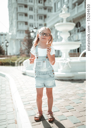 Little girl eating ice-cream in the street. 55284630