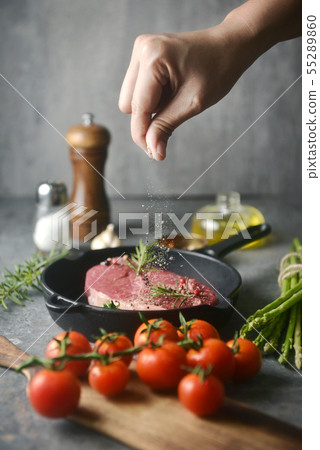 Hand sprinkle pepper for marinate meat in iron pan 55289860