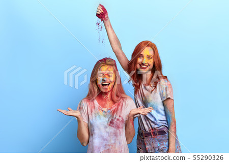 funny ginger girl throwing colored powder on her friend's head 55290326