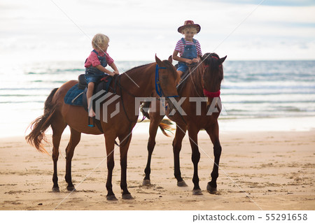 Kids riding horse on beach. Children ride horses. 55291658