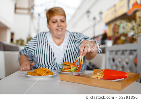 Fat woman eating french fries in mall food court Fat woman eating french fries in mall food court 55291856