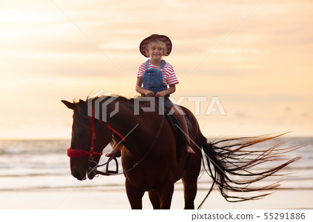Kids riding horse on beach. Children ride horses. 55291886