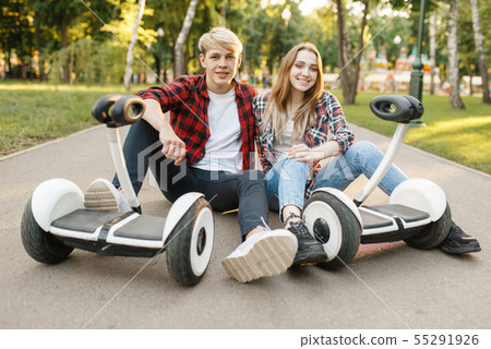Young couple sitting on road with gyro board 55291926