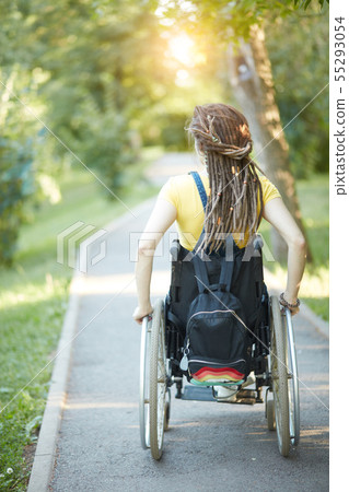 Young woman with pigtails in wheelchair outdoors 55293054
