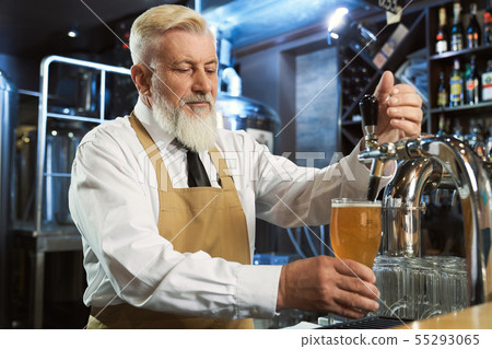 Barman pouring in cold glass lager beer. Barman pouring in cold glass lager beer. 55293065