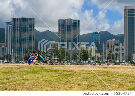 Woman doing bicycle maintenance near Ala Moana Beach Park, Magic Island Woman doing bicycle maintenance near Ala Moana Beach Park, Magic Island 55294754