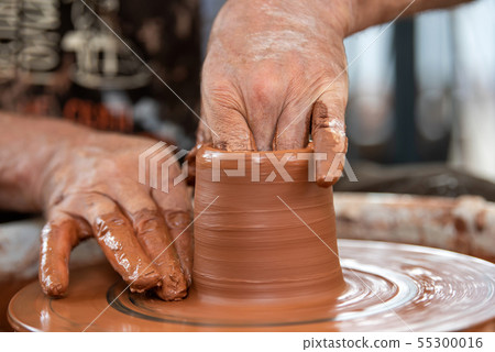 Potter makes pottery dishes on potter's wheel 55300016