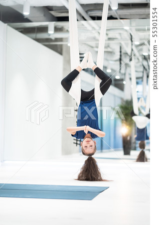 portrait of a beautiful young girl engaged in fly yoga on canvases. 55301554
