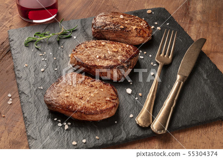 Sirloin or fillet beef steaks with salt, rosemary, and red wine on a black slate plate 55304374