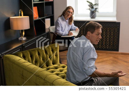 Surprised brown-haired middle-aged man sitting on the couch 55305421
