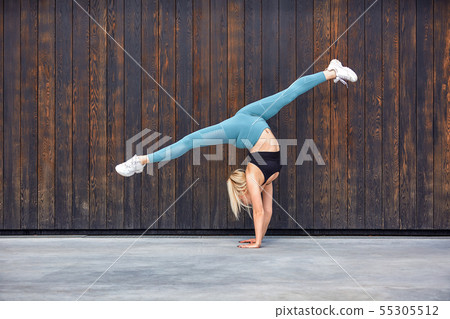 Beautiful athletic young girl gymnast in sportswear, working out, element of gymnastics, doing the 55305512
