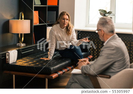 Mature blonde woman sitting next to her psychologist Mature blonde woman sitting next to her psychologist 55305997