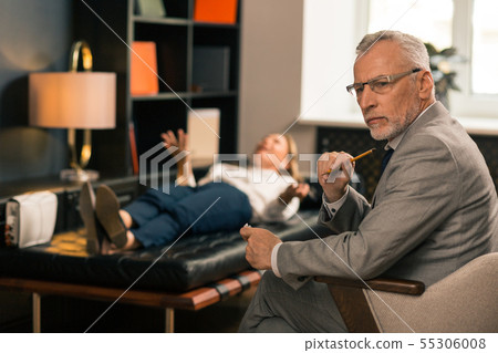 Handsome serious grey-haired psychiatrist sitting in his office 55306008