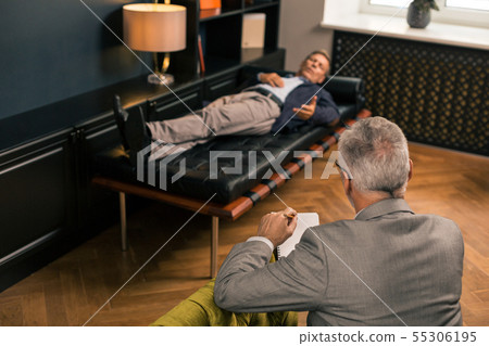 Professional psychologist sitting and listening to a patient 55306195