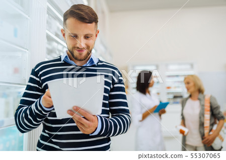 Positive delighted brunette male reading his prescription 55307065