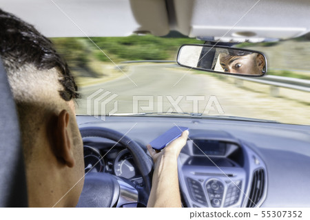 Young driver, using smartphone, on the road in the Young driver, using smartphone, on the road in the 55307352