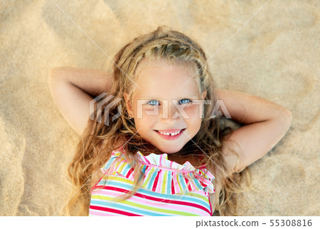 Pretty little blonde girl portrait lying on sandy beach during summer vacation 55308816