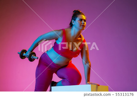 Young caucasian plus size female model's training on gradient background Young caucasian plus size female model's training on gradient background 55313176